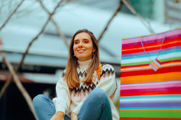 Woman Sitting and relaxing next to a Big Shopping Bag. Cheerful lady resting after a shopping spree...