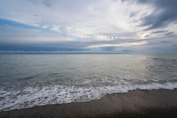 An incoming wave on the Black Sea coast against the sunset sky, Sochi, Krasnodar Territory, Russia