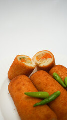 Risoles, traditional snack form Indonesia. It filled with carrot, potato, chicken and other vegetables rolled in breadcrumbs then deep fried, served with green chili on a plate on white background.