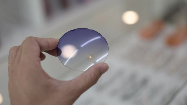 close up of a hand holding a glasses lens in optical store 