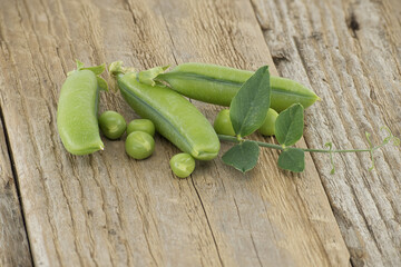 Group of fresh green peas with leaves on wooden surface