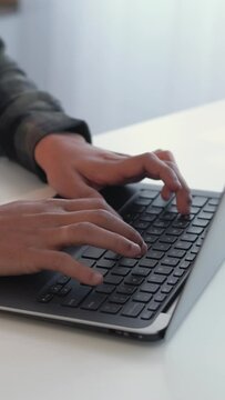 Vertical video. Laptop study. Online learning. Home education. Man student hands typing university homework essay at modern notebook at desk.