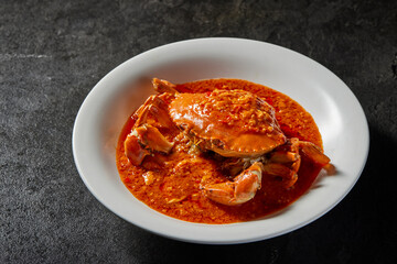 traditional chinese wok fried seafood fresh big meat crab with chilli spicy salted egg yolk cheese cream sauce in plate on dark stone table asian cafe hotel luxury halal food restaurant banquet menu