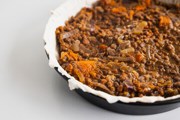 plant-based lentil and pumpkin pie with filling just poured into the pastry before cooking it
