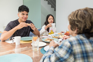 Grandson smiling and looking grandmother at family breakfast at home