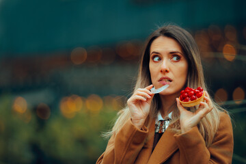 Woman Taking off her Retainer Eating a Fruit tart. Braces wearer being afraid she will stain the...