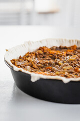 plant-based lentil and pumpkin pie with filling just poured into the pastry before cooking it