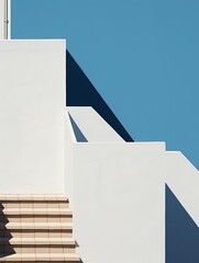 Minimalist architecture with geometric shapes, sharp shadows, and blue sky, highlighting modern design and simplicity.