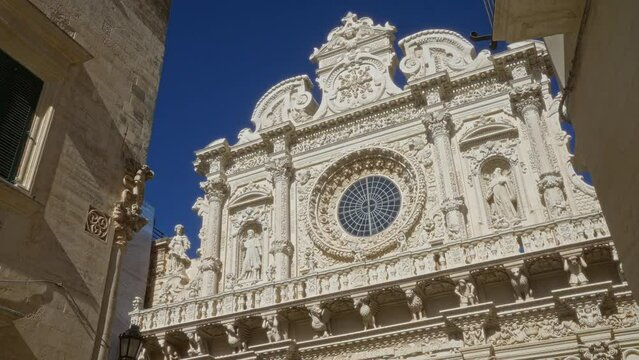 The intricate facade of the basilica of santa croce in lecce, puglia, italy, showcases stunning baroque architecture under a clear blue sky.