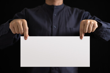 The hand of an Asian working man is holding a blank white sheet of paper for filling in text.