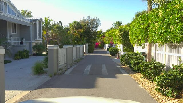 Car point of view driving on scenic road in sunny Florida. Casey Key coastal residential community picturesque streets.