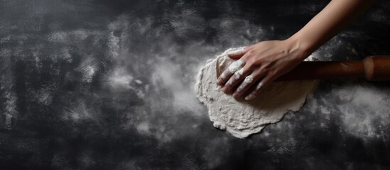 Hands put dough with flour on a dark black table,