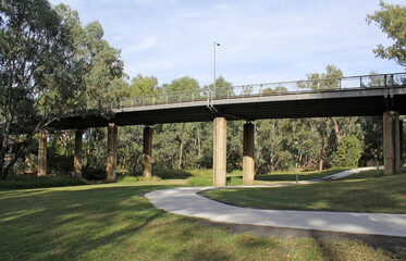 Bridge over the Mehi River with trees, grass, pathway and sky in Moree, New South Wales, Australia