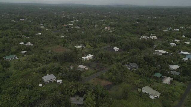 The lush, green, rural area of Hawaiian Paradise Park / Keaau on Hawaii's Big Island is shown from an aerial flyover view during the day.