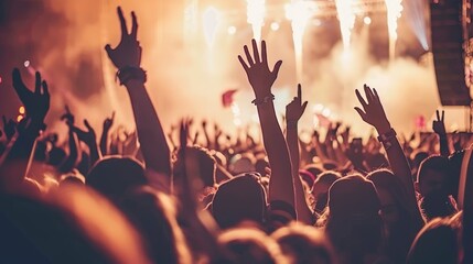 Fototapeta premium Energetic crowd with raised hands enjoying live music concert with vibrant lights and smoke-filled atmosphere.