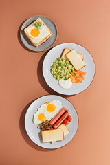 Minimalist Breakfast Composition with Fried Eggs, Toast, Scrambled Eggs, and Sausages on Neutral Background