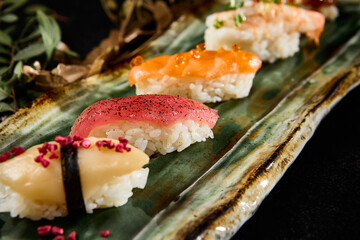 Assorted Sushi Platter with Salmon, Tuna, Shrimp, Eel, and Scallop on Green Ceramic Dish
