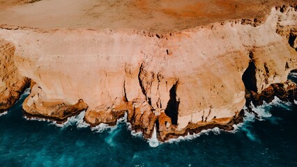 Aerial View of Turquoise Blue Ocean Beach With Crashing Waves and Red Dirt Sand and Rocks
