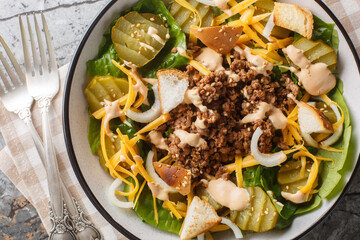 American Cheeseburger Salad with romaine lettuce, ground beef, pickles, cheddar cheese, onions and...