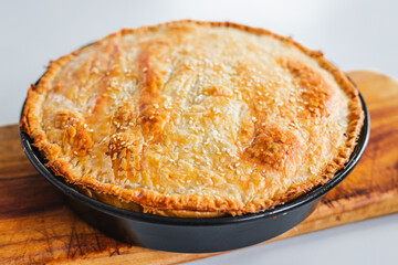 homemade round puff pastry pie in style of a sheperd's pie with sesame seeds topping just out of the oven