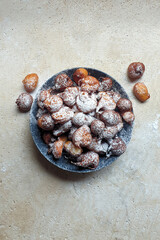 Croatian food, fritule in bowl sprinkled with icing sugar on stone table, sweet mini fritters ·