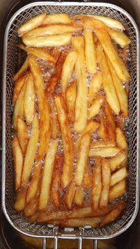 French fries is cooking into deep fryer. frying in hot boiling oil. Top view