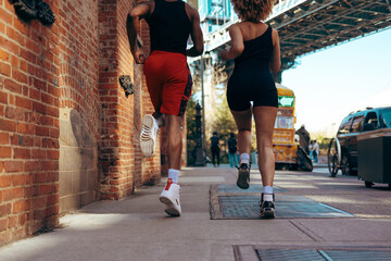 Rear view of a man and a woman running on a city street