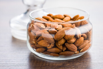 Peeled almond nuts in jar on wooden table.