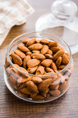 Peeled almond nuts in jar on wooden table.