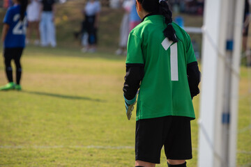 Young girl soccer goalkeeper looking at her team making an attack during the match. Youth U11...