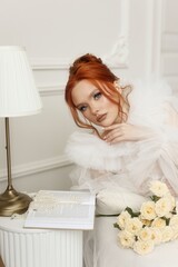 Elegant and poised, a young woman with fiery red hair and expert makeup looks mesmerizing in a...