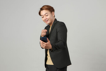 portrait of happy asian businessman wearing suit holding mobile phone on isolated background