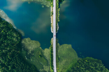 Aerial view of bridge asphalt road with cars and blue water lake and green woods in Finland.