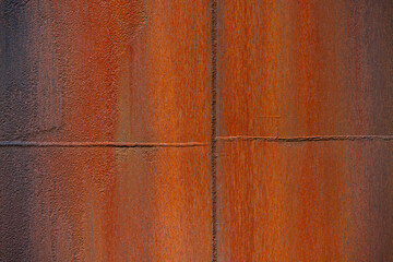 Rusted round steel tank or pipe with a corroded surface in the shades of orange, brown, red,...