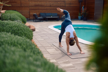 Athletic woman practicing Yoga in downward facing dog pose outdoors.