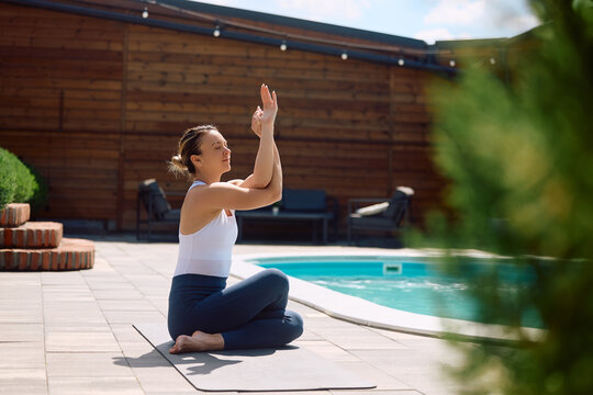 Athletic woman practicing Yoga in cow face pose with eagle arms pose.