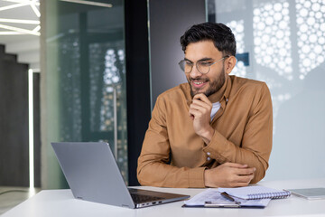 Young professional working on laptop in modern office environment