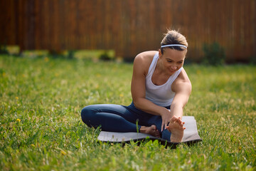 Happy female athlete doing stretching exercises in nature.