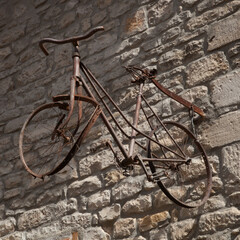 Vieux vélo rouillé accroché à un mur de pierres