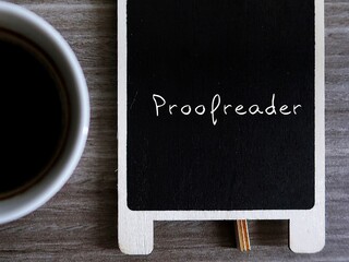 Blurred coffee cup and chalkboard with text written PROOFREADER, means a job in publishing...