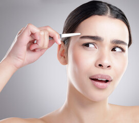 Woman, pain and eyebrow tweezer in studio with skincare, cosmetics and dermatology concern. Young...