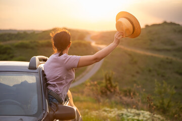 Girl with hat in the window of the car. Adventure, vacation, road trip concept.