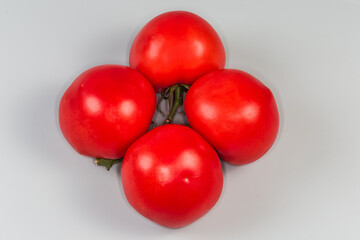 Red tomatoes on branch on a gray background, top view