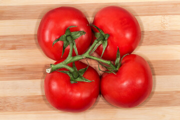 Red tomatoes on branch on cutting board, top view