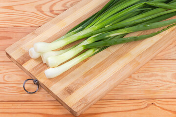 Stems of peeled young green onion on a cutting board