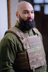 Bald bearded military man wearing buletproof vest