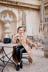 Young prety woman wearing coat is sitting in outdoor cafe in Wien.