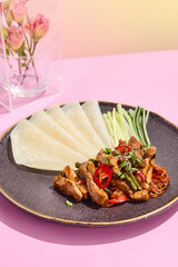 Sweet and sour chicken with rice pancakes and cucumbers in Beijing style; a fusion of taste and...