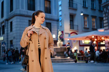 Portrait of beautiful caucasian woman wearing coat is walking by night Wien street.