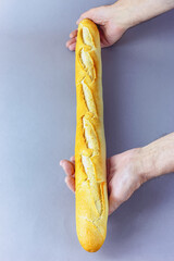 Fresh long french baguette with notches in man's hands